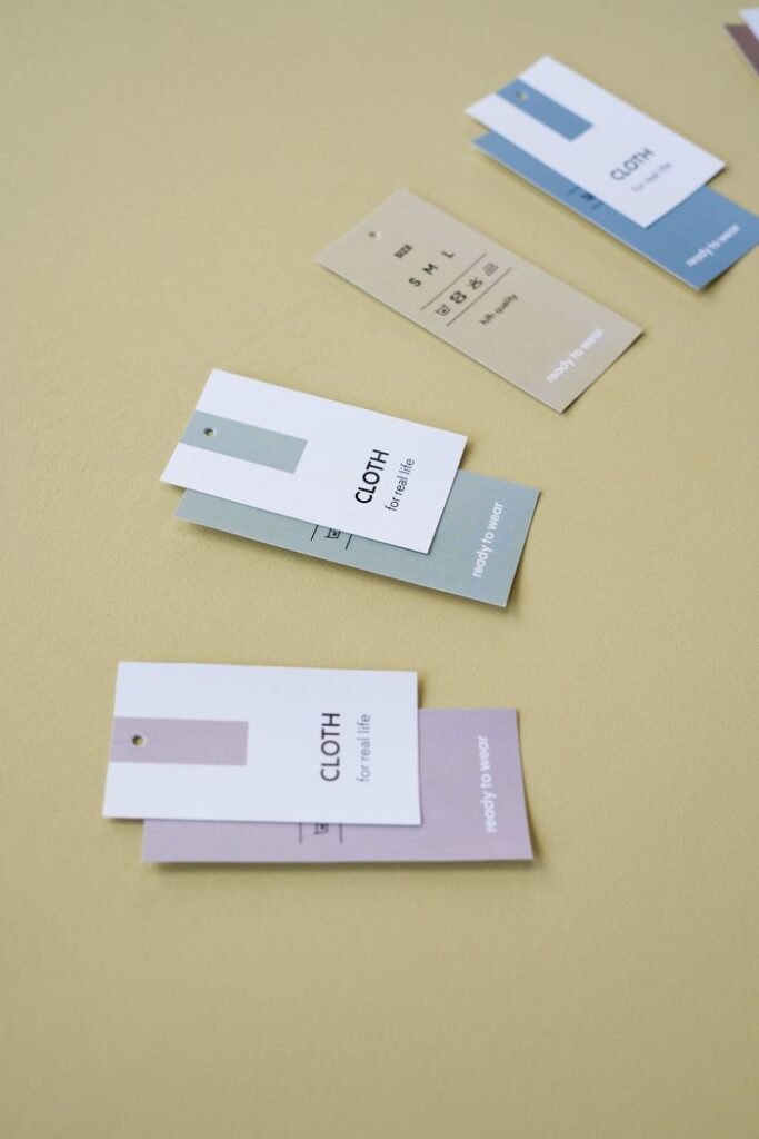 Close-up of minimalist clothing tags placed on a soft yellow surface, showcasing fashion and branding concepts.
